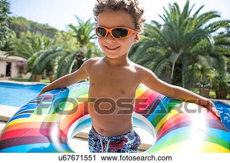 Boy holding inflatable ring on poolside View Large Photo Image Stock Image - Boy holding inflatable ring on poolside. Fotosearch