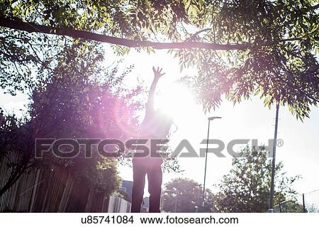 Picture - Boy jumping up to reach tree branch in sunlight. Fotosearch