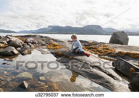 Boy looking at fjord rockpool, Aure, More og Romsdal, Norway View Large Photo Image Stock Photo - Boy looking at fjord rockpool, Aure, More og Romsdal, Norway. Fotosearch