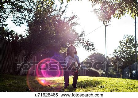 Boy looking up at tree in sunlight View Large Photo Image Stock Photography - Boy looking up at tree in sunlight. Fotosearch