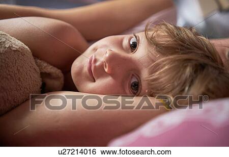 Stock Photograph - Boy lying in bed with mother, close up portrait. Fotosearch