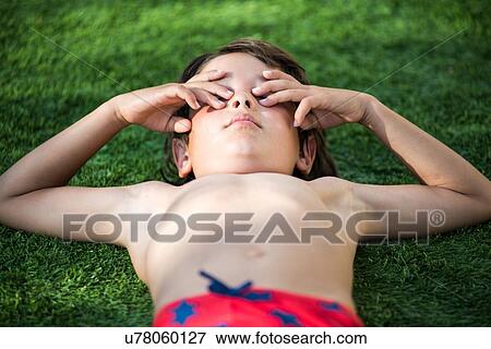 Boy lying on grass covering eyes View Large Photo Image Stock Photo - Boy lying on grass covering eyes. Fotosearch