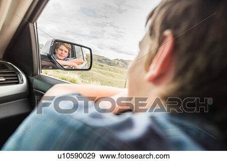 Boy on road trip leaning out of car window View Large Photo Image Stock Photo - Boy on road trip leaning out of car window. Fotosearch
