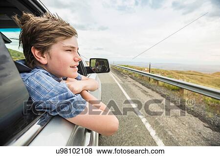 Boy on road trip leaning out of car window View Large Photo Image Stock Photo - Boy on road trip leaning out of car window. Fotosearch