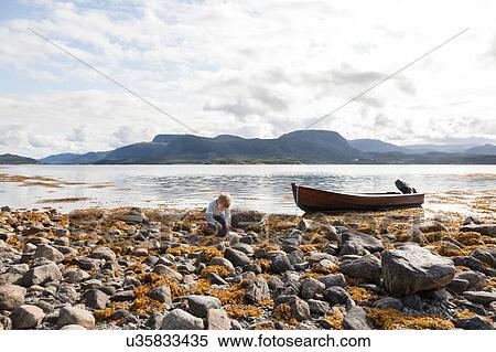 Stock Photography - Boy playing amongst rocks by fjord, Aure, More og Romsdal, Norway. Fotosearch