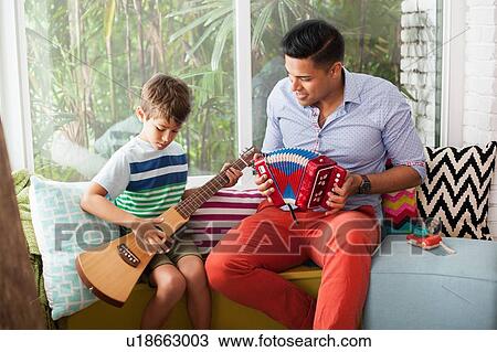 Boy playing guitar with music teacher on window seat View Large Photo Image Stock Image - Boy playing guitar with music teacher on window seat. Fotosearch