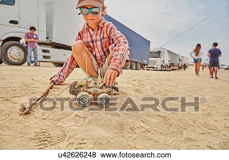 Stock Photo - Boy playing with toy truck in sand, Ica, Peru. Fotosearch