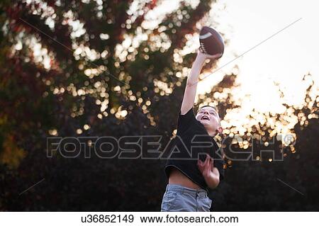Boy practicing american football in garden reaching to catch ball View Large Photo Image Stock Photo - Boy practicing american football in garden reaching to catch ball. Fotosearch