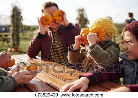 Stock Photo - Boy with sister and father fooling around with vegetable squashes in pumpkin patch field. Fotosearch