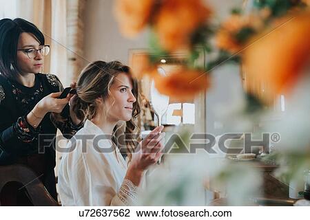 Stock Image - Bride preparing for wedding with hairstylist. Fotosearch