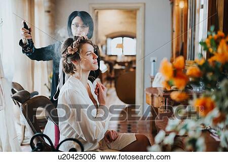 Stock Photograph - Bride preparing for wedding with hairstylist. Fotosearch