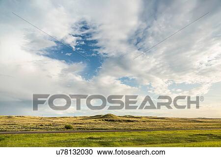 Stock Image - Bright cloudscape over flat rural landscape, Montana, US. Fotosearch