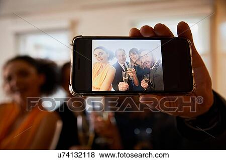 Stock Photo - Business team raising champagne toast at office celebration, smartphone selfie close up. Fotosearch