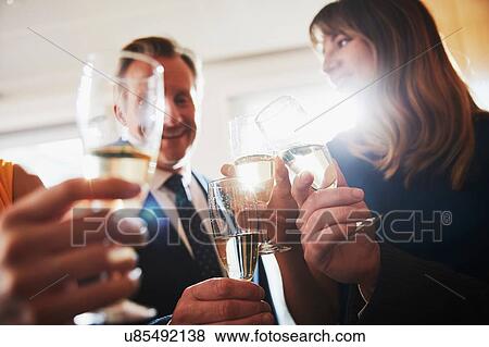 Stock Photo - Business team raising champagne toast at office celebration. Fotosearch