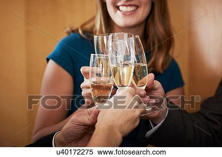 Stock Photography - Business team raising champagne toast at office celebration, cropped. Fotosearch