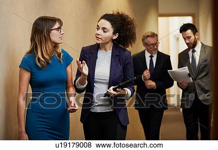 Stock Photo - Business team walking and talking along office corridor. Fotosearch