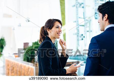 Stock Image - Businessman and businesswoman having drink at bar. Fotosearch