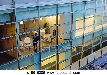 Businessman and businesswoman having discussion by window View Large Photo Image Stock Photograph - Businessman and businesswoman having discussion by window. Fotosearch