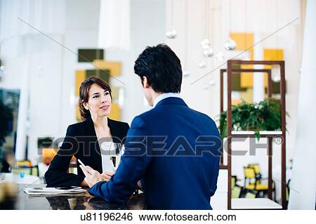 Stock Photograph - Businessman and businesswoman having drink at bar. Fotosearch
