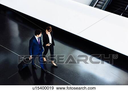 Businessman and businesswoman with wheeled luggage in hotel building View Large Photo Image Stock Photo - Businessman and businesswoman with wheeled luggage in hotel building. Fotosearch