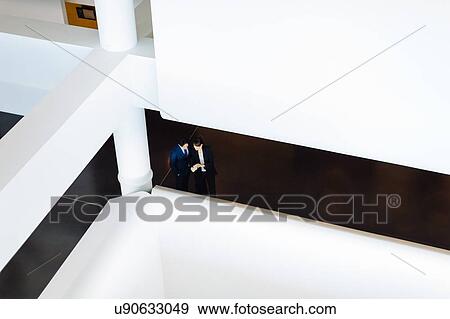 Businessman and businesswoman with wheeled luggage in hotel building View Large Photo Image Stock Photo - Businessman and businesswoman with wheeled luggage in hotel building. Fotosearch