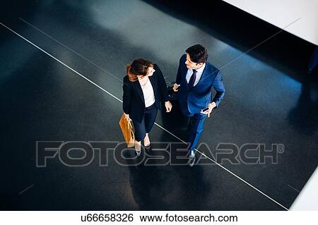 Businessman and businesswoman with wheeled luggage in hotel building View Large Photo Image Stock Photograph - Businessman and businesswoman with wheeled luggage in hotel building. Fotosearch