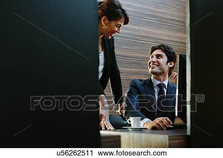 Stock Image - Businessman and businesswoman working in business centre in hotel. Fotosearch