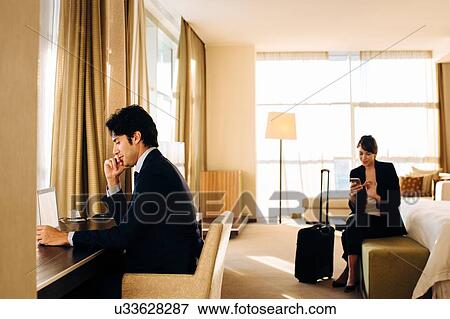 Stock Photo - Businessman and businesswoman working in hotel bedroom. Fotosearch