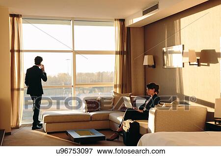 Stock Photo - Businessman and businesswoman working in hotel bedroom. Fotosearch