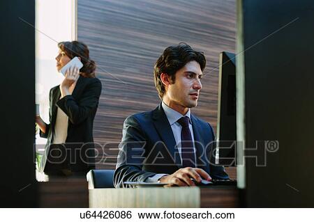 Stock Photograph - Businessman and businesswoman working in business centre in hotel. Fotosearch