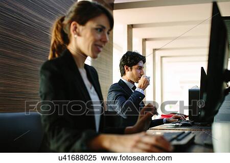 Stock Photography - Businessman and businesswoman working in business centre in hotel. Fotosearch