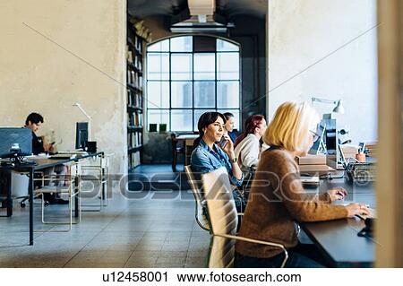 Businessman and businesswomen sitting in office, working View Large Photo Image Stock Image - Businessman and businesswomen sitting in office, working. Fotosearch