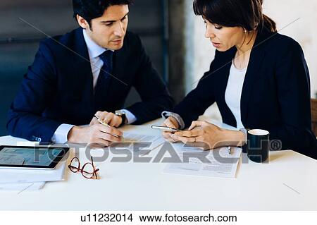 Businessman and woman in meeting, businesswoman looking at smartphone View Large Photo Image Picture - Businessman and woman in meeting, businesswoman looking at smartphone. Fotosearch