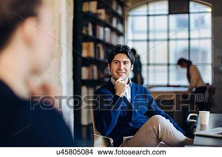 Picture - Businessman and woman in office, sitting, in conversation. Fotosearch