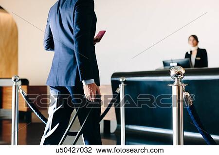 Stock Image - Businessman checking in at hotel reception. Fotosearch