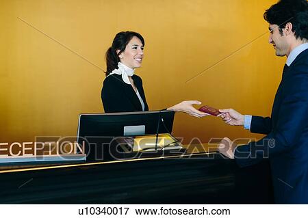 Stock Photo - Businessman checking in at hotel reception. Fotosearch