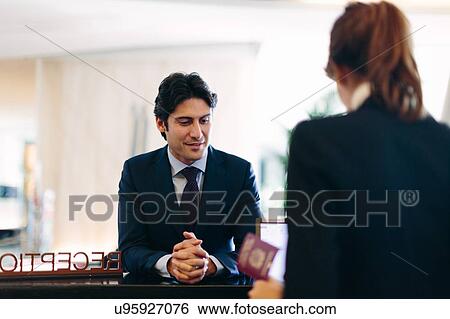 Businessman checking in at hotel reception View Large Photo Image Stock Photograph - Businessman checking in at hotel reception. Fotosearch
