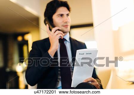 Stock Image - Businessman ordering room service in hotel. Fotosearch