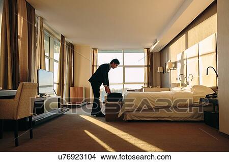 Picture - Businessman packing luggage in hotel bedroom. Fotosearch