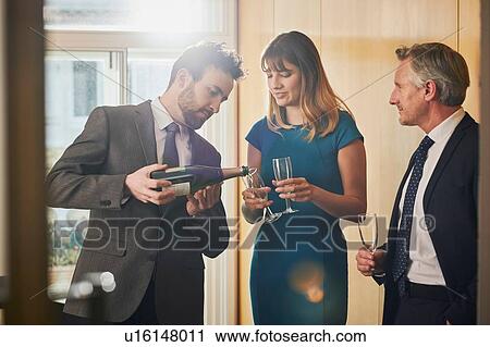 Businessman pouring champagne at office celebration View Large Photo Image Stock Image - Businessman pouring champagne at office celebration. Fotosearch