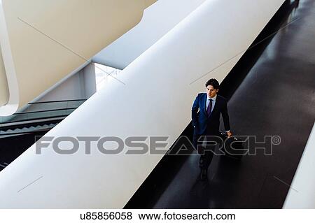 Businessman with wheeled luggage in hotel building View Large Photo Image Stock Photo - Businessman with wheeled luggage in hotel building. Fotosearch
