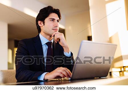 Stock Image - Businessman working in business centre in hotel. Fotosearch