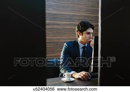 Stock Photograph - Businessman working in business centre in hotel. Fotosearch