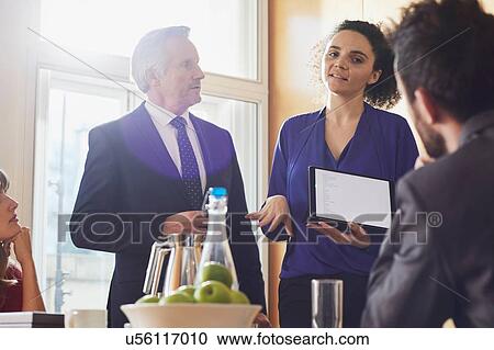 Stock Image - Businesswoman and male colleague giving presentation on digital tablet during office meeting. Fotosearch