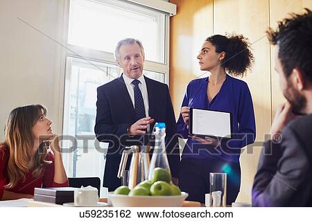 Businesswoman and male colleague giving presentation on digital tablet during office meeting View Large Photo Image Stock Image - Businesswoman and male colleague giving presentation on digital tablet during office meeting. Fotosearch