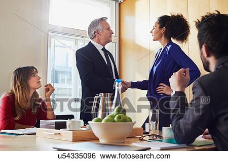 Businesswoman and man shaking hands at office meeting View Large Photo Image Stock Photograph - Businesswoman and man shaking hands at office meeting. Fotosearch