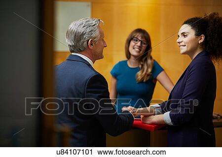 Stock Image - Businesswoman and man shaking hands in reception. Fotosearch