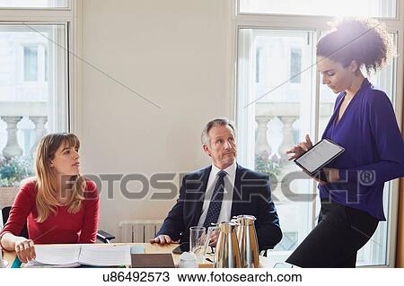 Stock Image - Businesswoman giving presentation on digital tablet during office meeting. Fotosearch