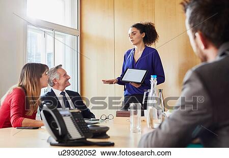 Stock Image - Businesswoman giving presentation during office meeting. Fotosearch