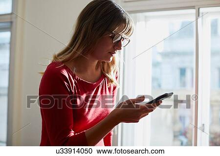 Businesswoman looking at smartphone in office View Large Photo Image Stock Image - Businesswoman looking at smartphone in office. Fotosearch